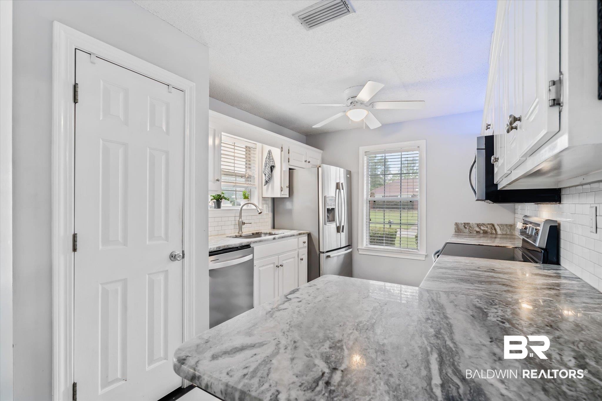 2320 Sequoya Trail Mobile, AL 36695 - Photo 7 of 20 Kitchen featuring tasteful backsplash, ceiling fan, white cabinets, sink, and appliances with stainless steel finishes