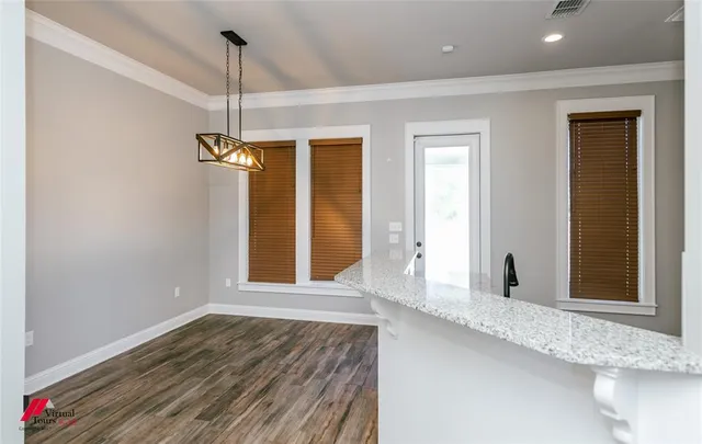 a view of an empty room with window and wooden floor