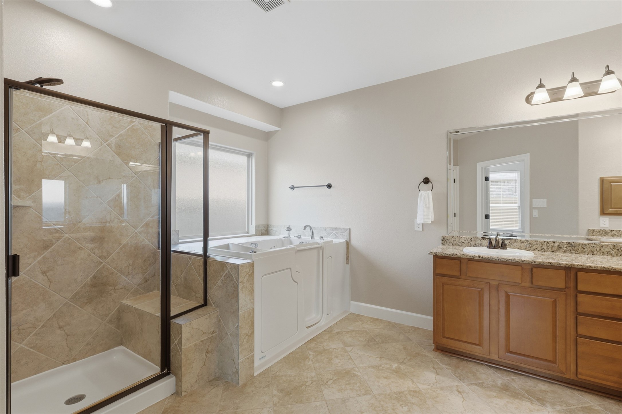 721 Rufina Street League City, TX 77573 - Photo 16 of 33 Designed for relaxation and accessibility, the spacious ensuite features a large walk-in shower with built-in bench and tiled surround alongside a premium walk-in soaking tub.