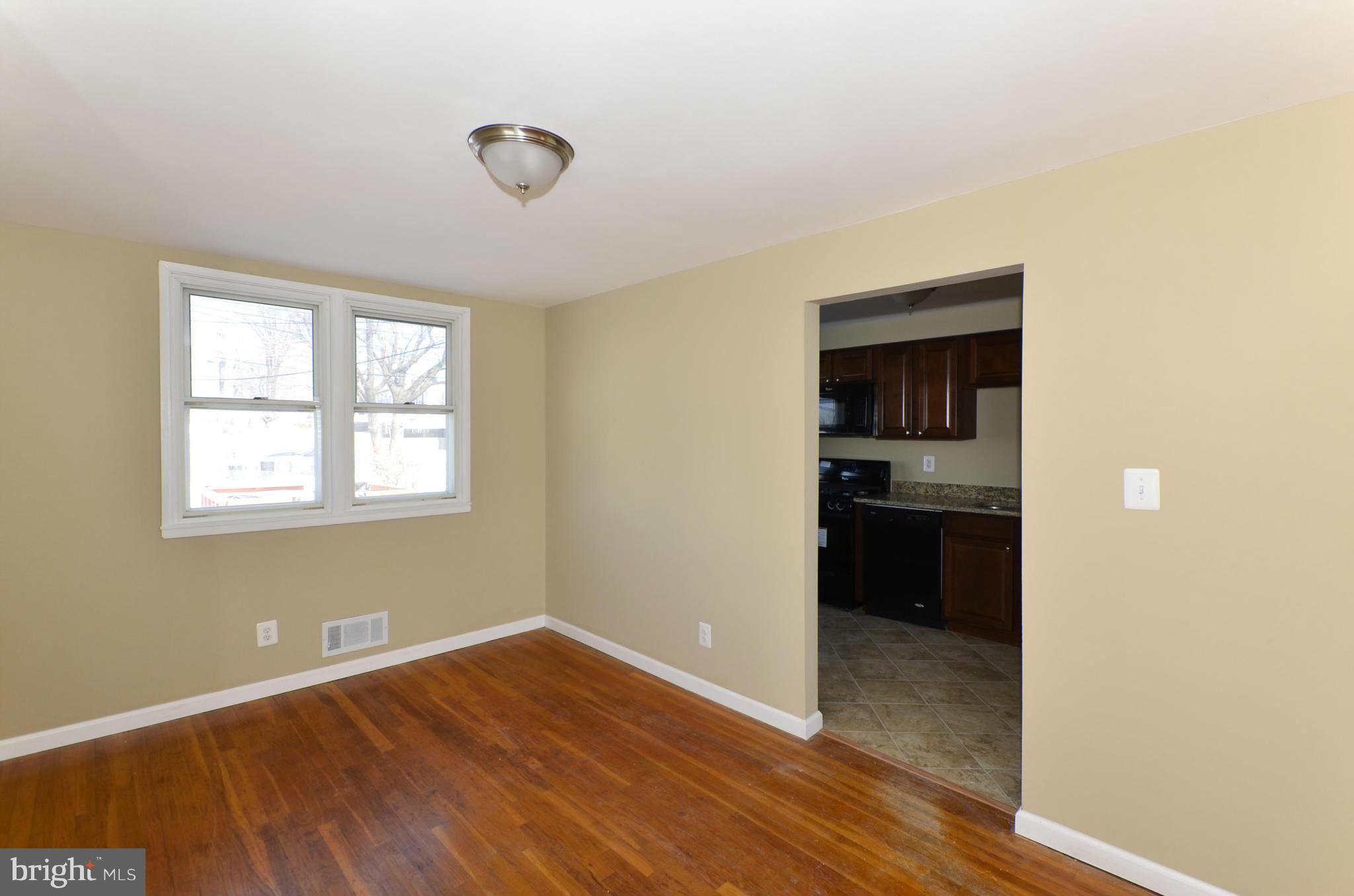 8058 Stratman Road Baltimore, MD 21222 - Photo 8 of 30 a view of a kitchen and an empty room with wooden floor and a window