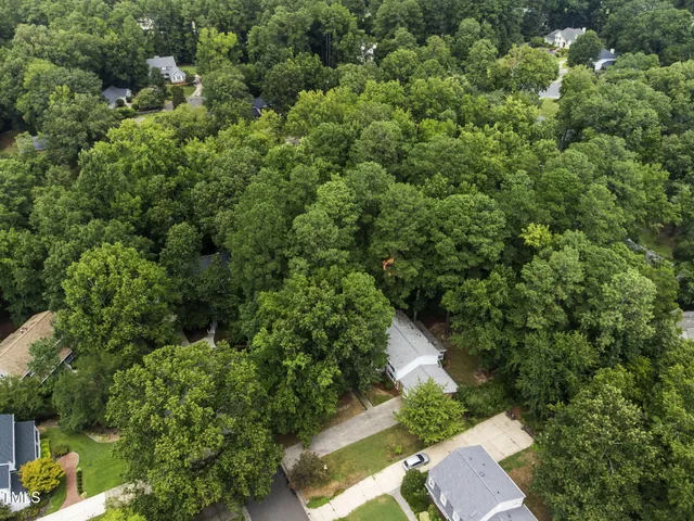 an aerial view of residential house with outdoor space and trees all around