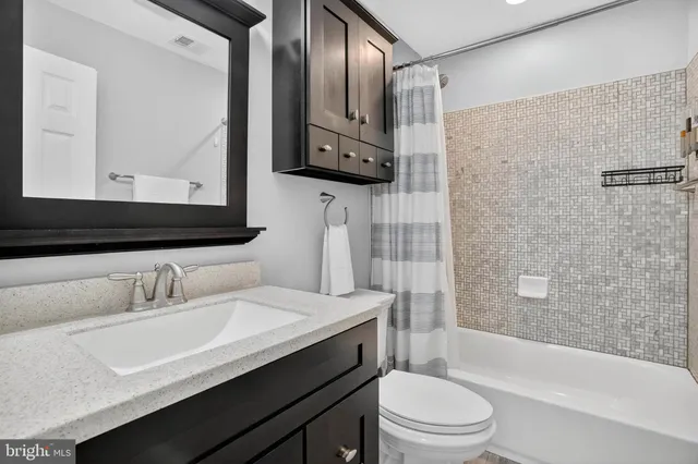 a bathroom with a sink a toilet a mirror and shower