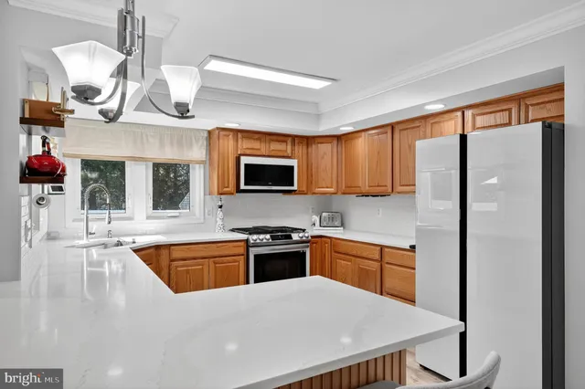 a kitchen with stainless steel appliances granite countertop a sink dishwasher a stove and a refrigerator with wooden floor