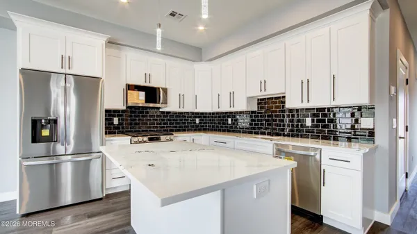 a kitchen with a sink a refrigerator and white cabinets