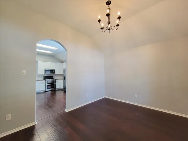 wooden floor in an empty room with a chandelier fan
