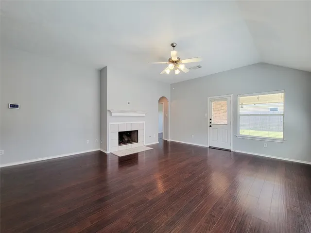a view of an empty room with a fireplace and wooden floor