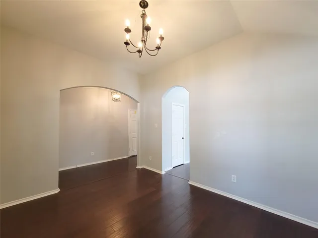 an empty room with wooden floor and hallway