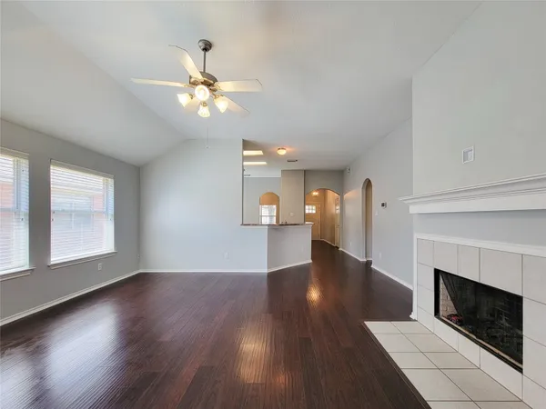 a view of a livingroom with wooden floor a ceiling fan and a fireplace