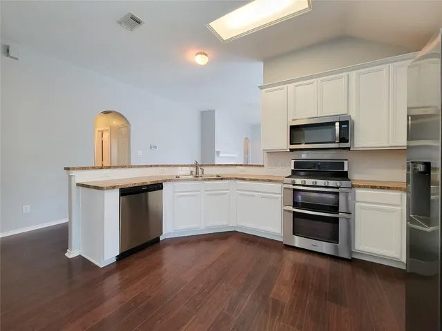 a kitchen with granite countertop a sink cabinets and stainless steel appliances