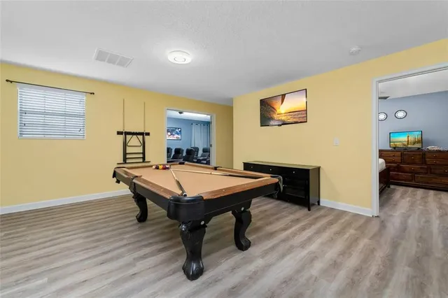 a room with furniture pool table and wooden floor