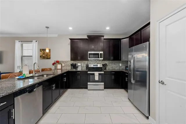 a kitchen with stainless steel appliances granite countertop a refrigerator a sink a stove a microwave and a refrigerator