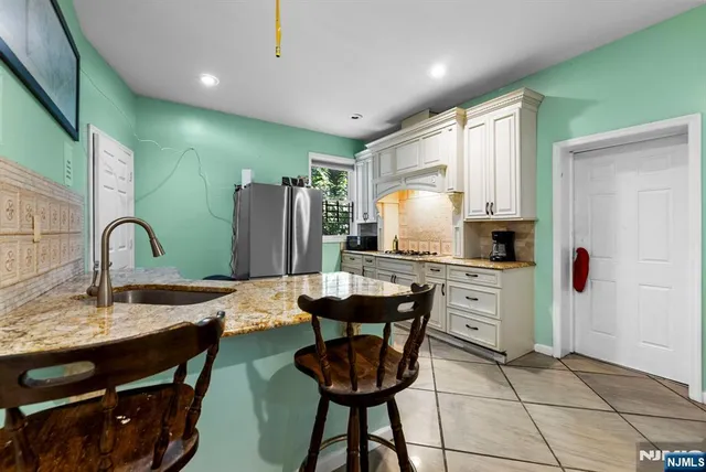 a kitchen with stainless steel appliances kitchen island granite countertop a sink a refrigerator and chairs