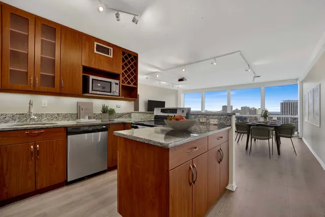 a kitchen with stainless steel appliances granite countertop a stove a sink dishwasher and a microwave oven with white cabinets