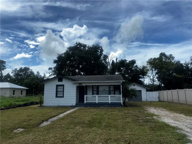 a front view of a house with a garden and trees