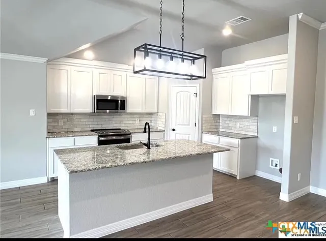 a kitchen with stainless steel appliances granite countertop a sink a stove and cabinets