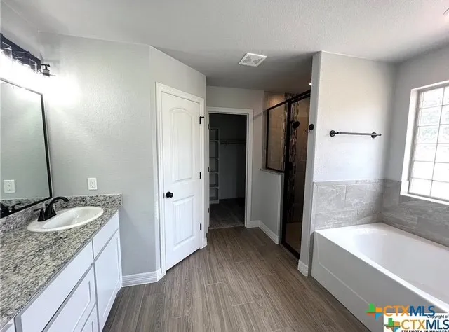 a bathroom with a granite countertop double vanity sink a mirror and a bathtub