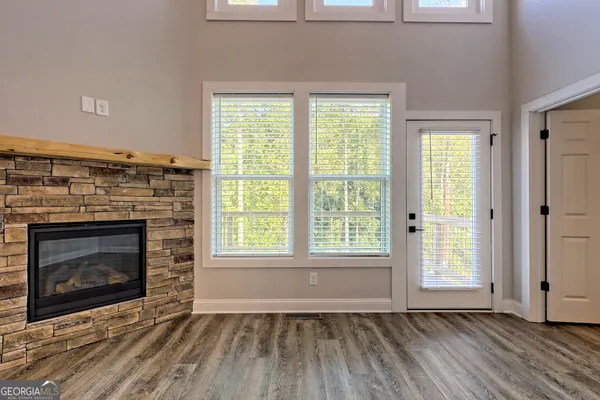 an empty room with wooden floor cabinet and windows