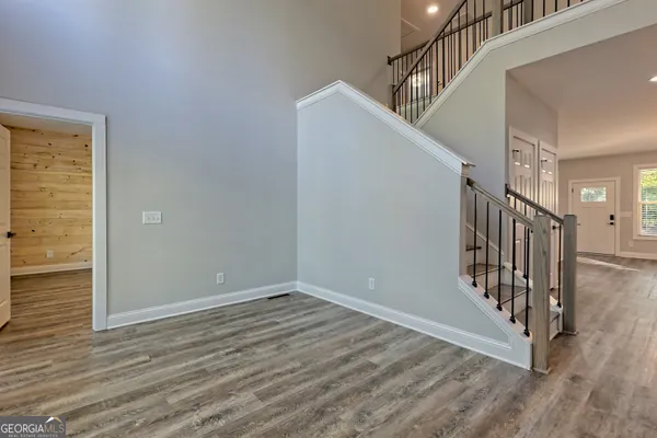 a view of a hallway with wooden floor and a bathroom