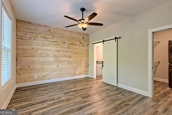 a view of empty room with wooden floor and fan