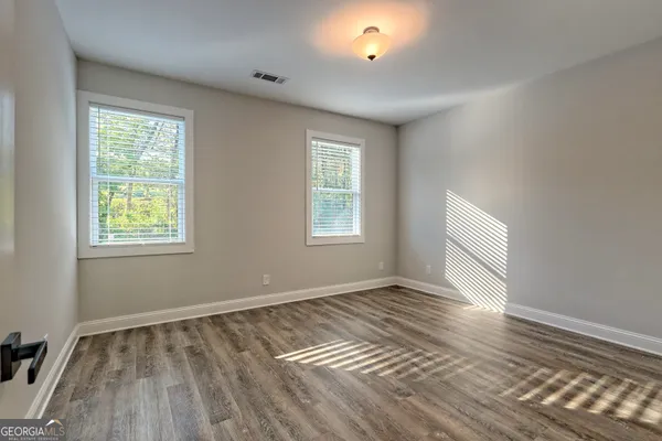 a view of empty room with wooden floor and fan