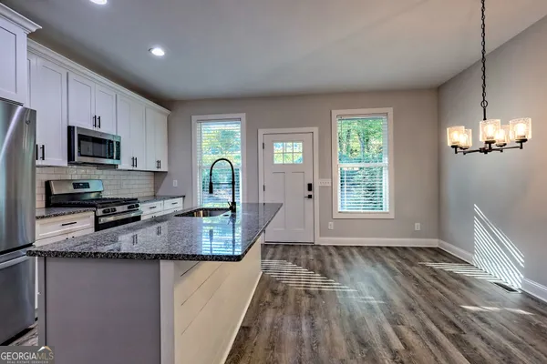 a view of an empty room with wooden floor fireplace and a window