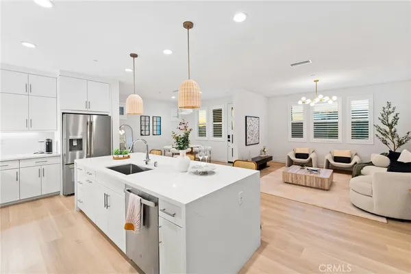 a kitchen with stainless steel appliances kitchen island granite countertop a dining table chairs sink refrigerator and cabinets