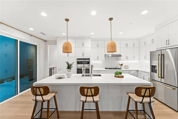 a kitchen with stainless steel appliances kitchen island granite countertop a table chairs stove and white cabinets