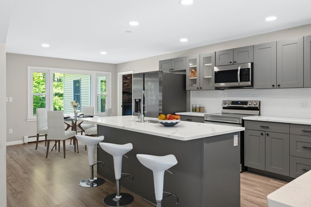 549 Main Street Townsend, MA 01474 - Photo 3 of 41 a kitchen with stainless steel appliances granite countertop a stove a sink a microwave a dining table and chairs with wooden floor