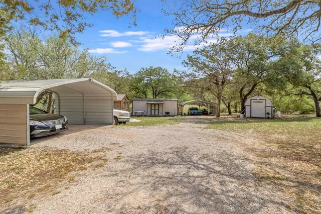 a view of a house with a yard and large tree