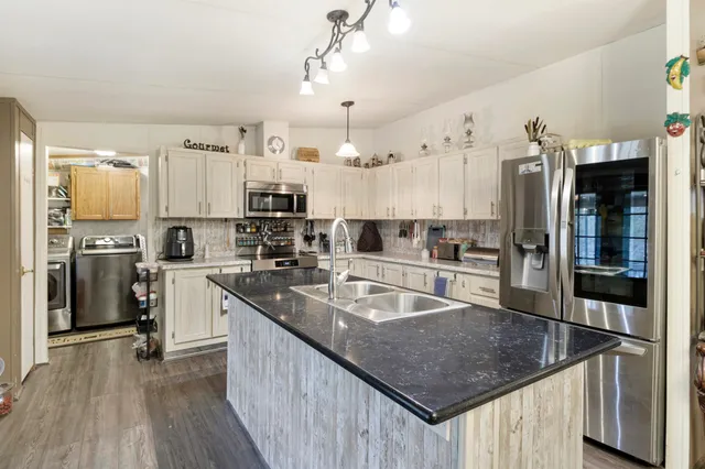 a kitchen with stainless steel appliances granite countertop a sink a stove and refrigerator