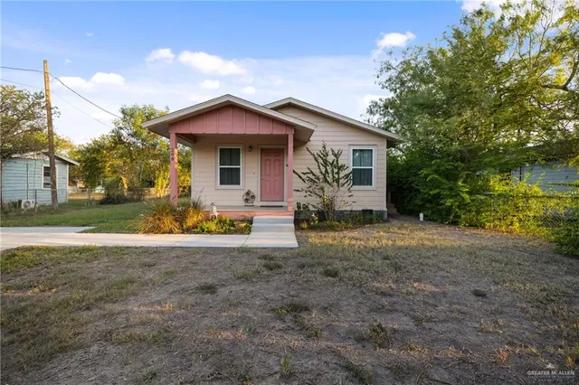 a view of a house with a yard and large tree