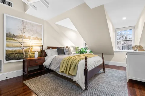 a bedroom with a bed wooden floor and window