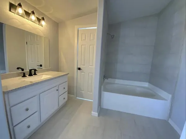 a spacious bathroom with a tub sink and mirror