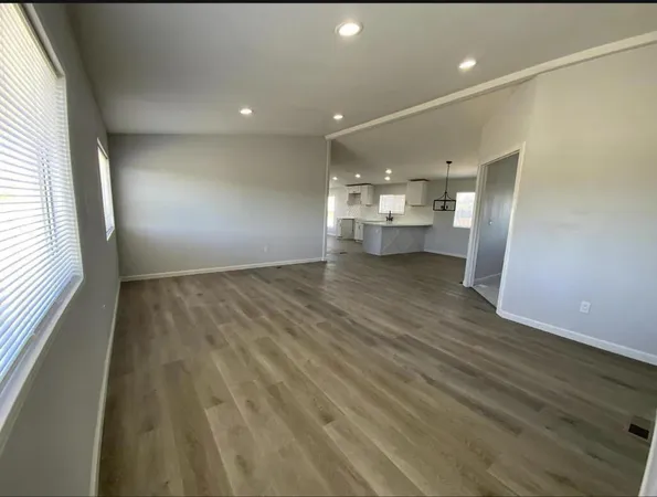 a view of a big room with wooden floor and windows