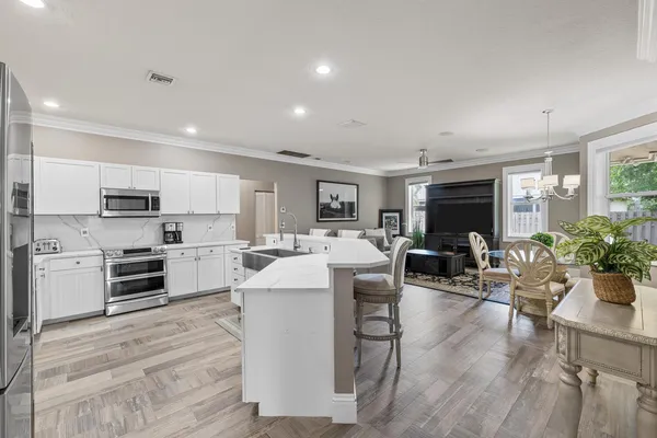 a kitchen with stainless steel appliances a dining table chairs refrigerator sink and cabinets