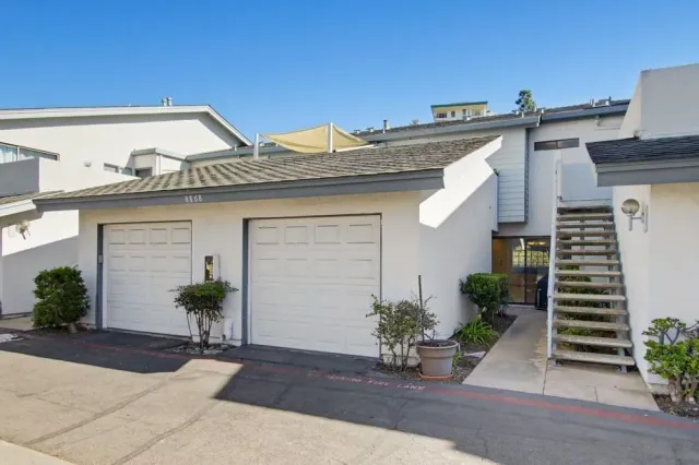 a view of a patio with table and chairs under an umbrella with palm trees