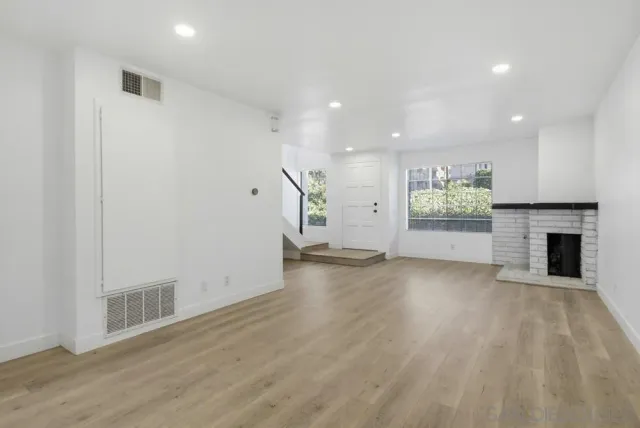 an empty room with wooden floor and a fireplace