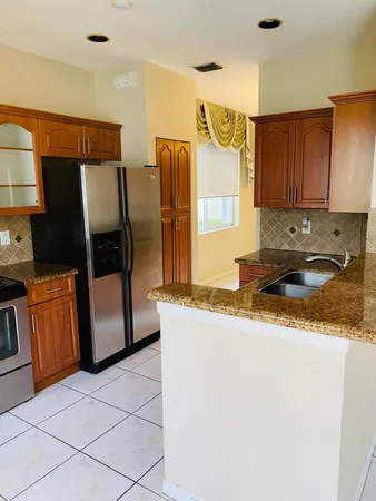 a kitchen with granite countertop a refrigerator and a stove top oven