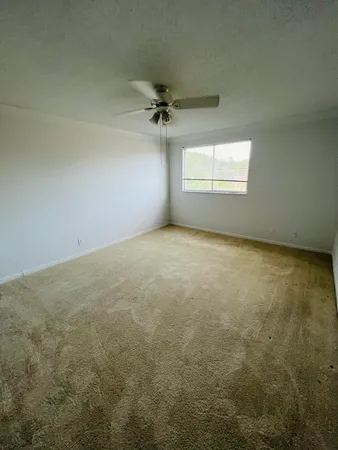 an empty room with a ceiling fan and window