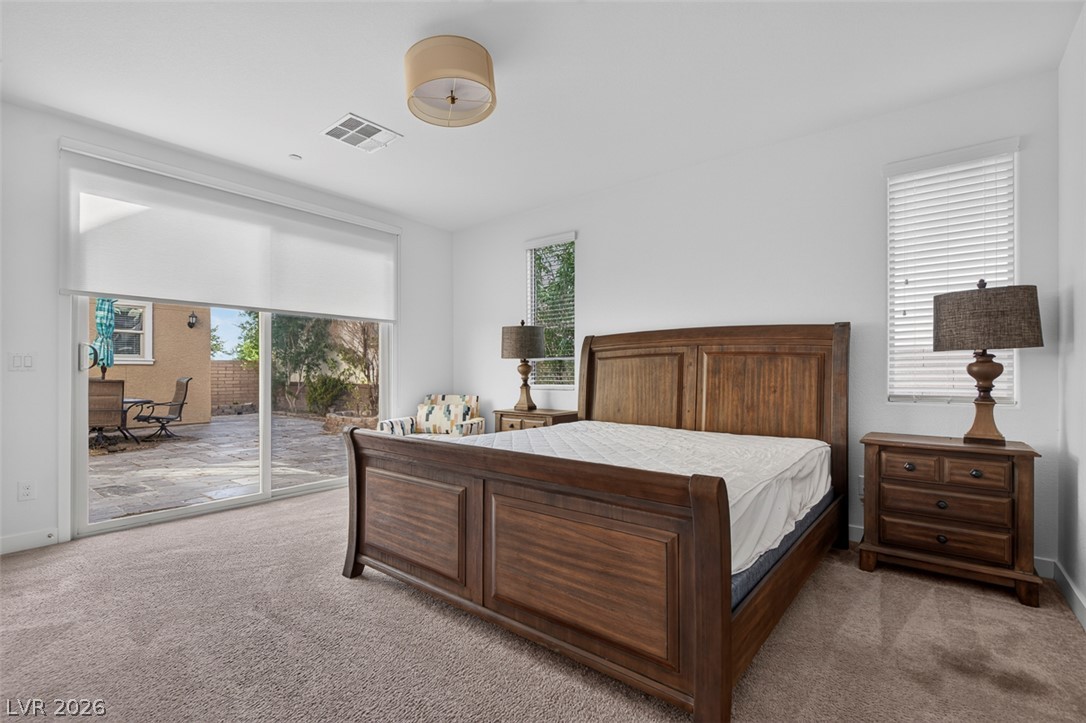 1100 East Sunset Road Henderson, NV 89011 - Photo 20 of 58 A spacious sleeping area with carpeted floors and a large sliding glass door opening to a private outdoor patio.