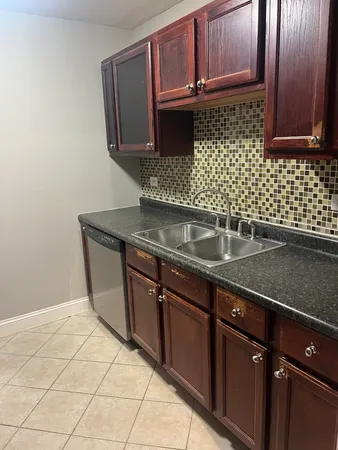 a kitchen with granite countertop a sink a stove and cabinets