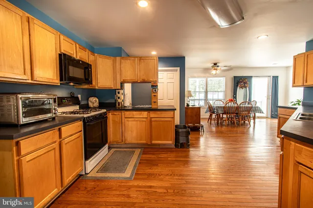 a kitchen with stainless steel appliances granite countertop a refrigerator a stove top oven a sink dishwasher and white cabinets with wooden floor