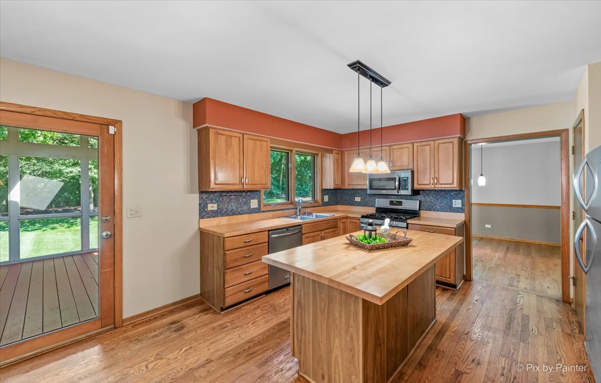 3001 Turnberry Road St. Charles, IL 60174 - Photo 12 of 46 a kitchen with a stove a refrigerator a sink a dining table and chairs with wooden floor