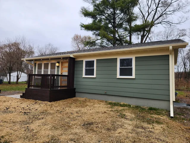 a view of a house with a wooden deck and furniture