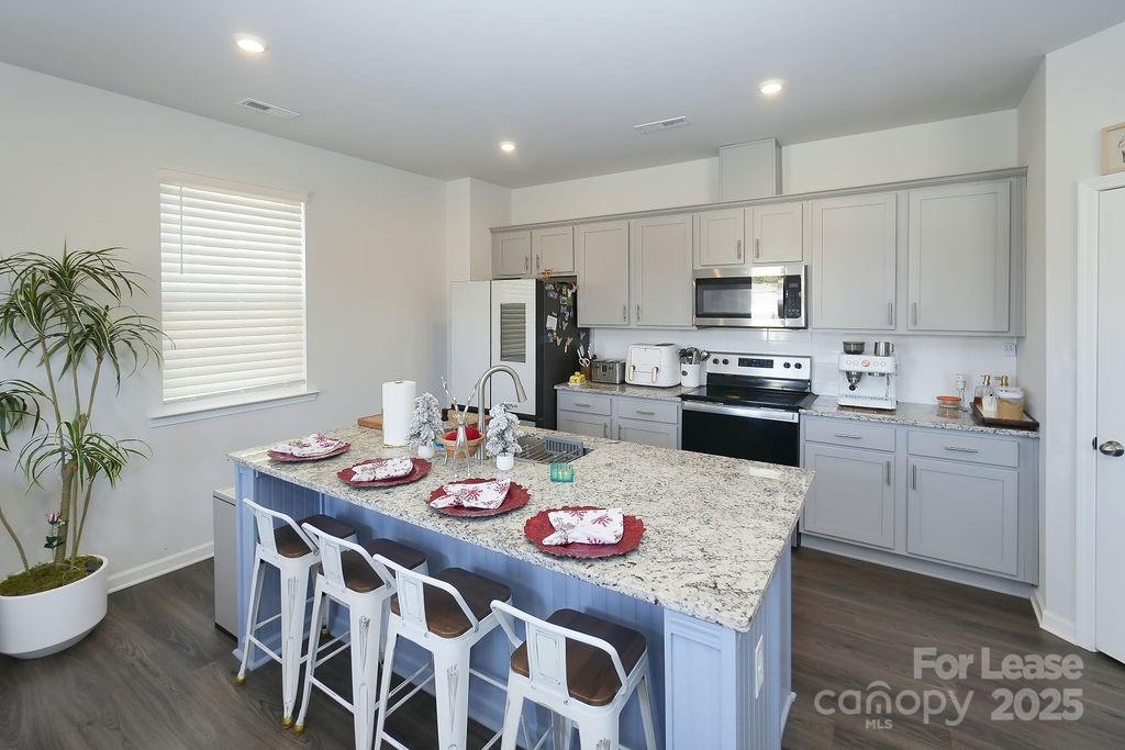547 Sitka Drive York, SC 29745 - Photo 6 of 20 a kitchen with stainless steel appliances granite countertop a stove a sink a refrigerator a microwave oven with a dining table and chairs
