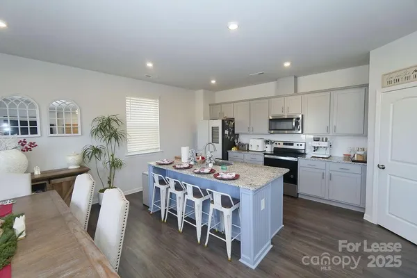 a kitchen with stainless steel appliances a stove a sink a refrigerator and white cabinets with wooden floor
