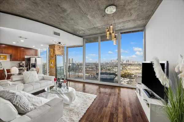 a living room with furniture floor to ceiling window and wooden floor