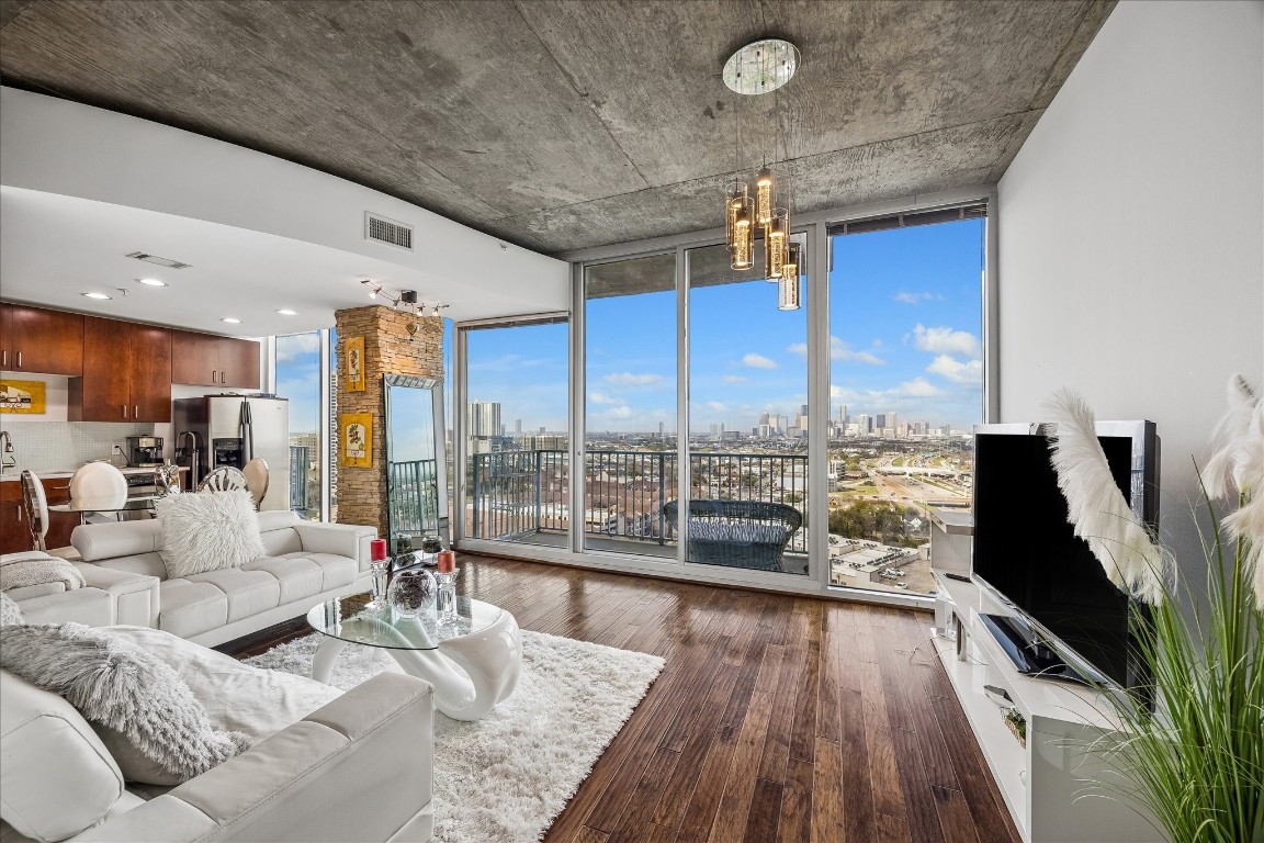 a living room with furniture floor to ceiling window and wooden floor