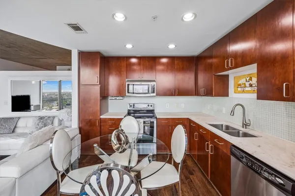 a kitchen with stainless steel appliances granite countertop a refrigerator and a stove top oven with wooden floor