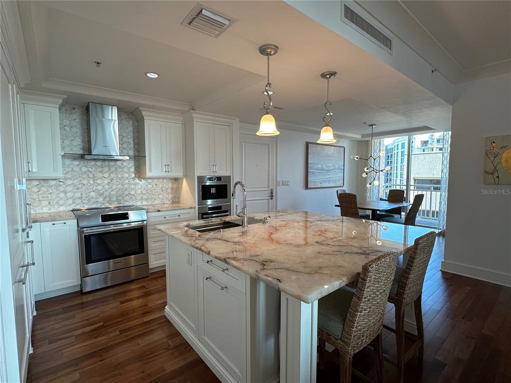 1350 Main Street, Unit 1401 Sarasota, FL 34236 - Photo 12 of 69 a kitchen with a stove a sink a dining table and chairs